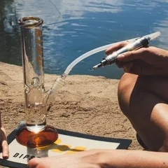 A person using a bong with an enail outside