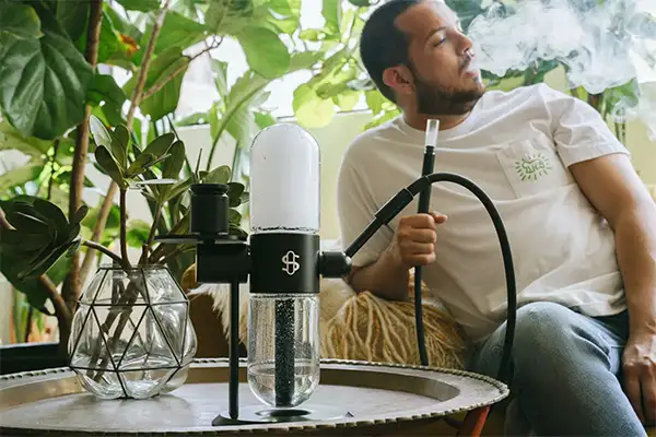 A man smokes a black gravity bong on the table