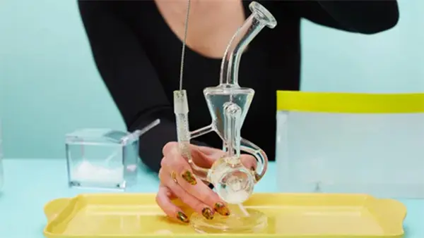 A woman in black is cleaning a dab rig