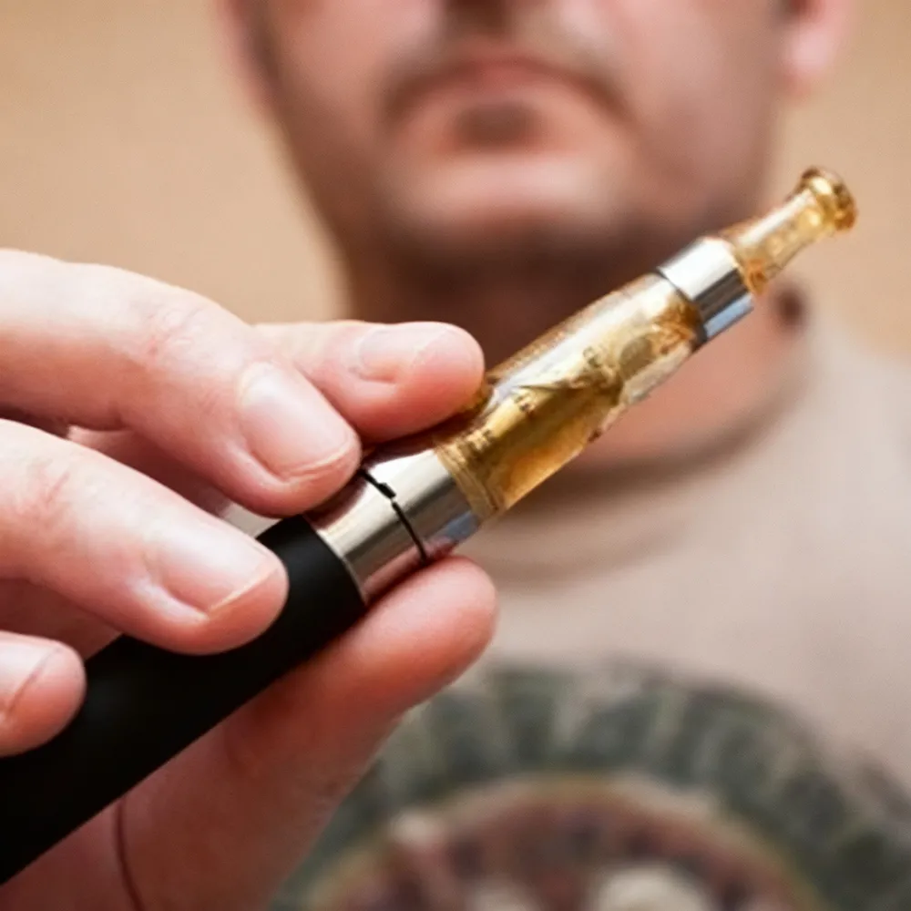 A man is holding a vape pen