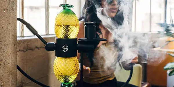 A woman smokes a pineapple gravity bong
