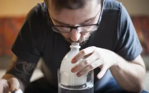A man is inhaling with the gravity bong