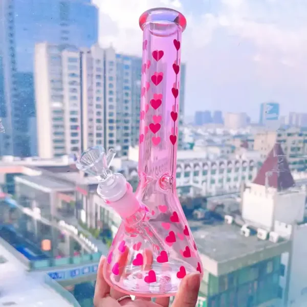 pink‑heart‑beaker‑bong Pink red heart printed beaker glass bong held in hand